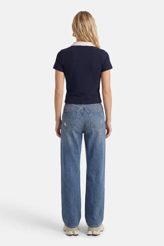 Polo bleu à manches courtes de ONLY®, vue de dos, avec un col blanc et associée à un jean.