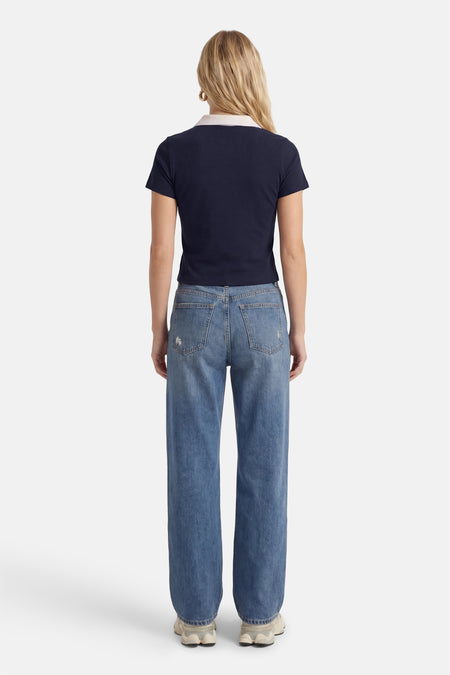 Blauwe polo met korte mouwen van ONLY®, gezien vanaf de achterkant, met een witte kraag en gecombineerd met jeans.