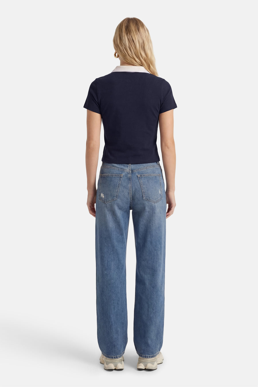 Polo bleu à manches courtes de ONLY®, vue de dos, avec un col blanc et associée à un jean.
