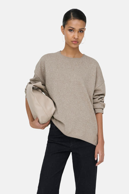 Beige trui met ronde hals van ONLY, met lange mouwen, gedragen met een zwarte jeans en beige handtas.
