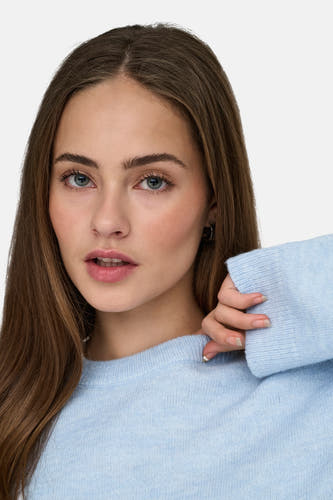 T-shirt bleu avec col rond de ONLY, porté par un modèle aux longs cheveux bruns et aux boucles d'oreilles.