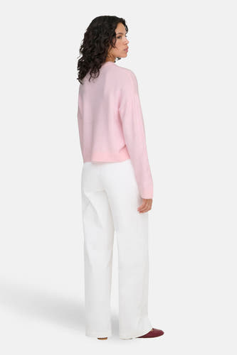 Roze trui met ronde hals van ONLY, gedragen met een witte broek en bordeauxrode ballerina's.
