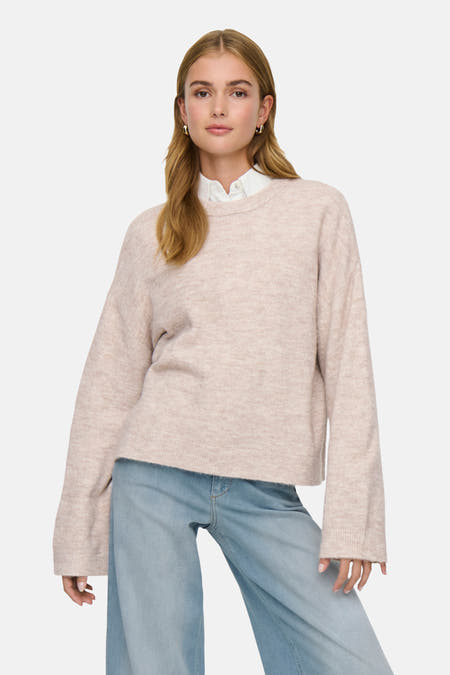 Beige trui met ronde hals van ONLY, gedragen met een wit overhemd en wijde jeans.
