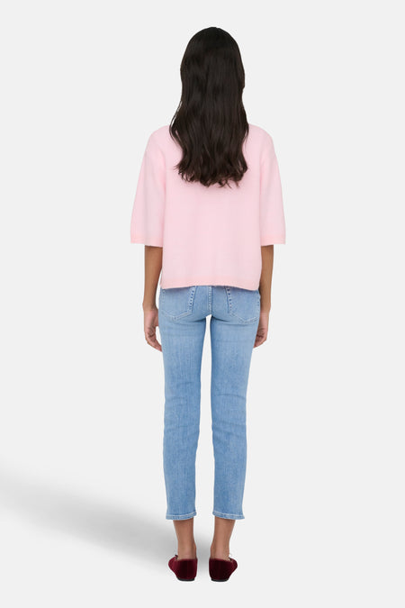 Vrouw van achter, roze trui, jeans, bordeauxrode ballerina's.