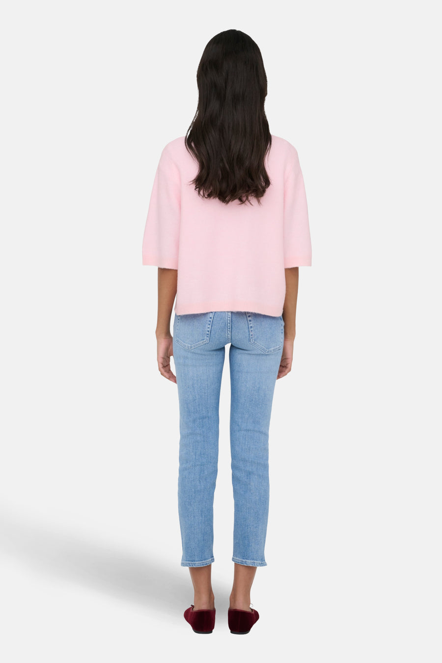 Vrouw van achter, roze trui, jeans, bordeauxrode ballerina's.