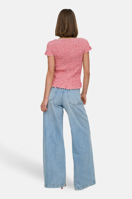 Rode T-shirt van ONLY met korte mouwen, een gerimpeld design en gedragen met een wijde jeans.
