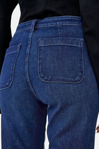 Jean flare bleu marine de ONLY, avec des poches brodées à l'arrière et une chemise noire.