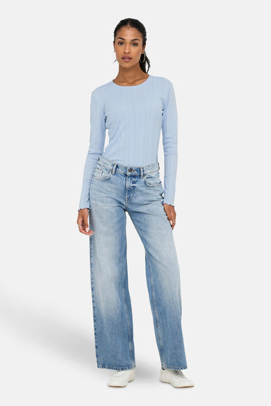 Blauw T-shirt met lange mouwen van ONLY, met ribstructuur, gecombineerd met wijde jeans en witte sneakers.
