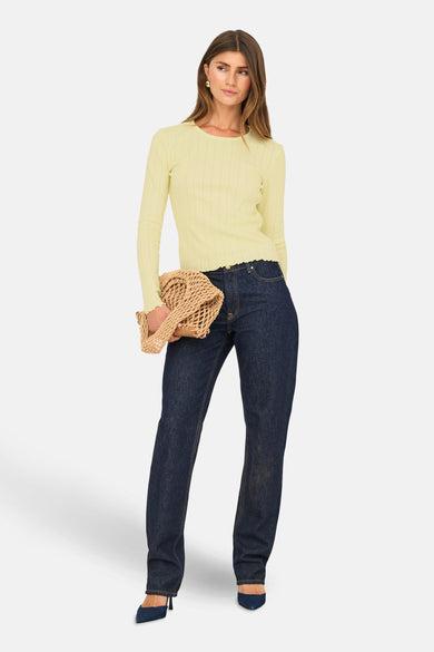 T-shirt jaune à manches longues de ONLY, avec des bordures côtelées, associé à des jeans foncés et une pochette en paille.
