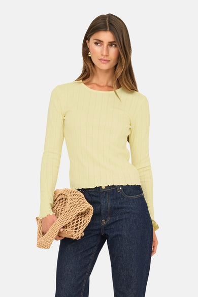 T-shirt jaune à manches longues de ONLY®, avec des bordures fines, porté avec des jeans foncés et un sac tressé.