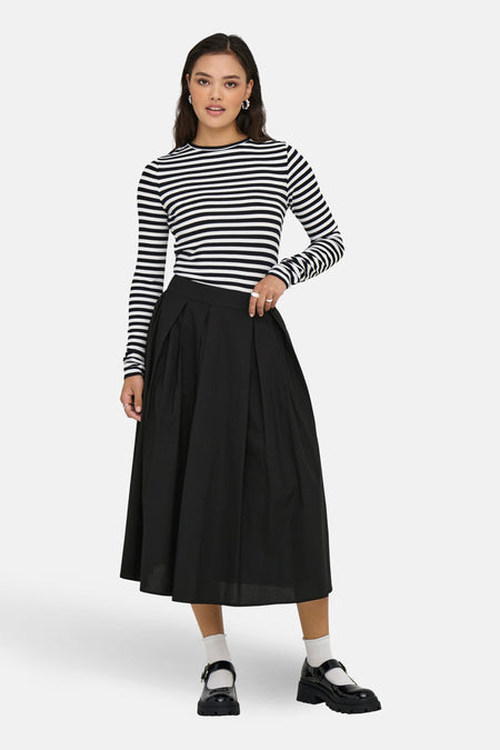 Lange zwarte rok van ONLY, met plooien en gecombineerd met een gestreepte top en plateauzool schoenen.

