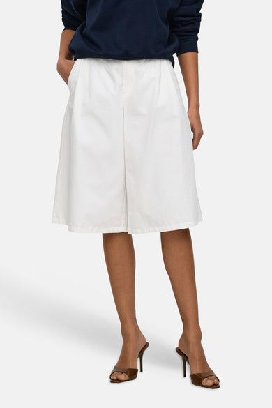 Witte short van JDY met losse pasvorm en licht kreukelige stof, gedragen door een model met navyblauwe trui en bruine hakken.