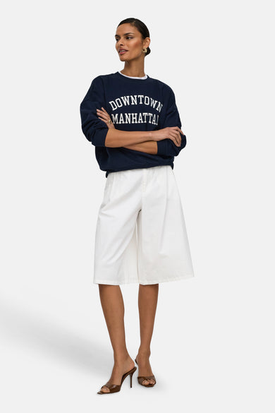 Witte shorts van JDY, gedragen door een model met een marineblauwe sweatshirt en bruine muiltjes.
