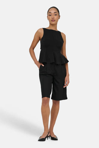 Haut noir sans manches de ONLY avec style péplum, porté avec un short noir et des escarpins slingback.