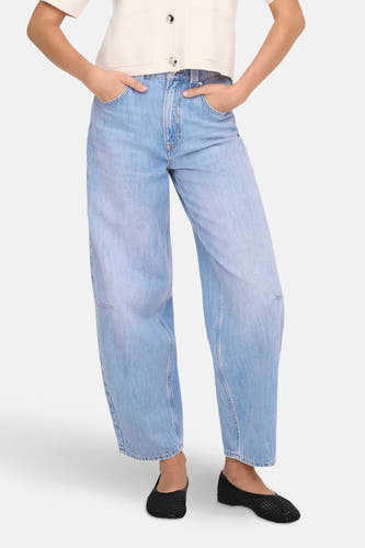 Jean spécial ajusté en denim bleu clair de ONLY®, avec des jambes larges et porté avec un t-shirt blanc crème et des chaussures noires.