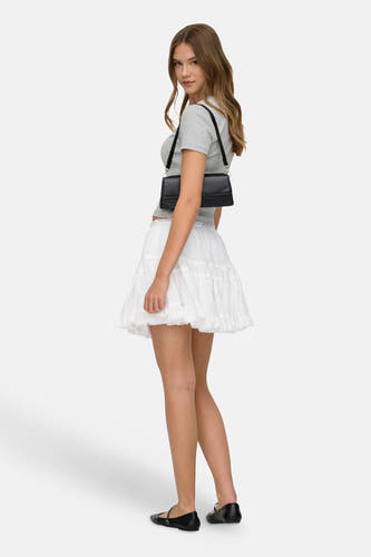 Jupe blanche ONLY® avec finition en dentelle et volants, portée par un mannequin avec un t-shirt gris et un sac à bandoulière noir.