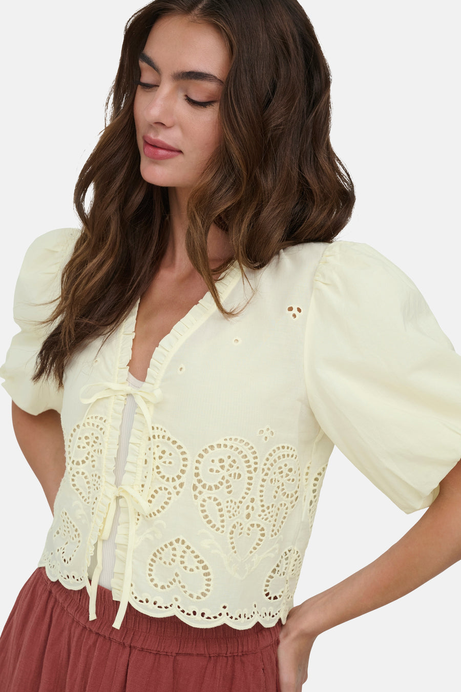 Chemise jaune à manches courtes ONLY®, avec broderie, volants et détail de nœud, portée avec une jupe marron-rouge.