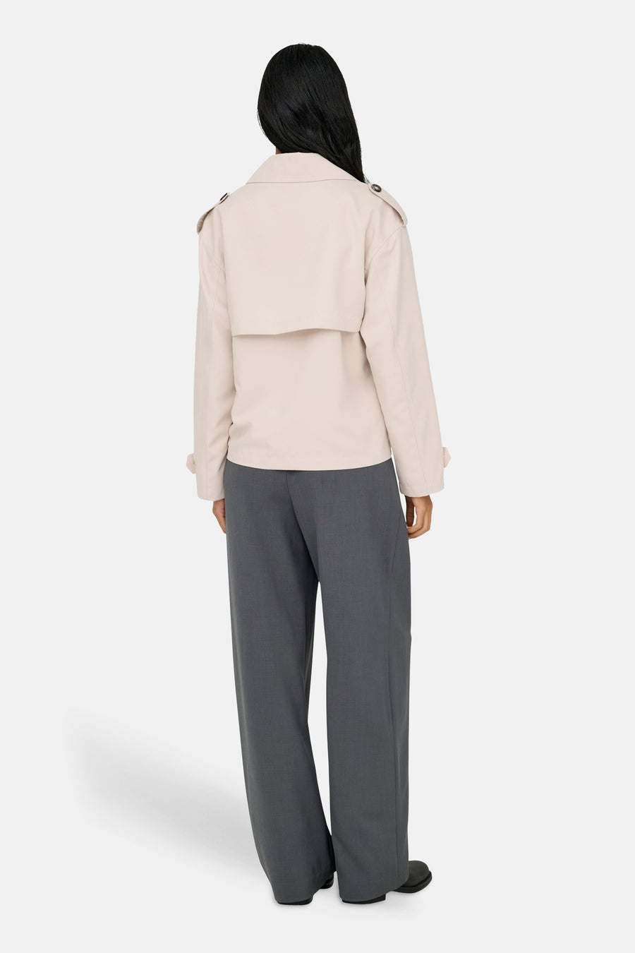 Manteau court beige de ONLY, avec détails d'épaules et porté avec un pantalon gris à jambes larges.