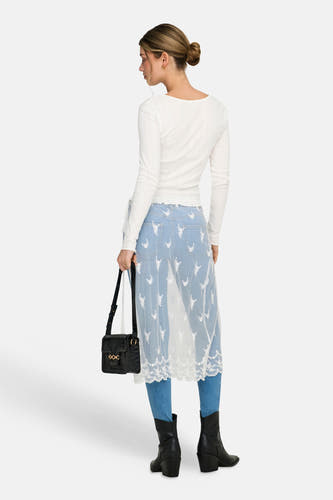 Jupe blanche ONLY, avec détails en dentelle et motif fleuri sur un jean avec bottes et sac.