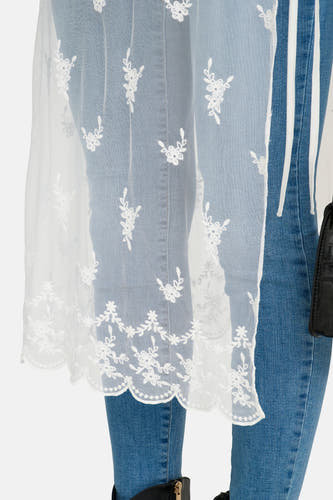 Jupe blanche ONLY, avec un motif floral en dentelle et un ourlet ondulé, portée sur un jean.