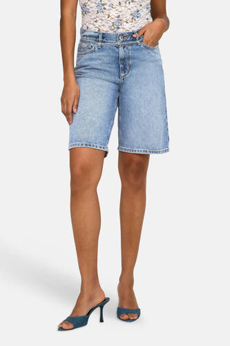 Short en jean bleu mi-long de ONLY®, longueur genou, combiné avec un haut en dentelle blanche et des sandales bleues.