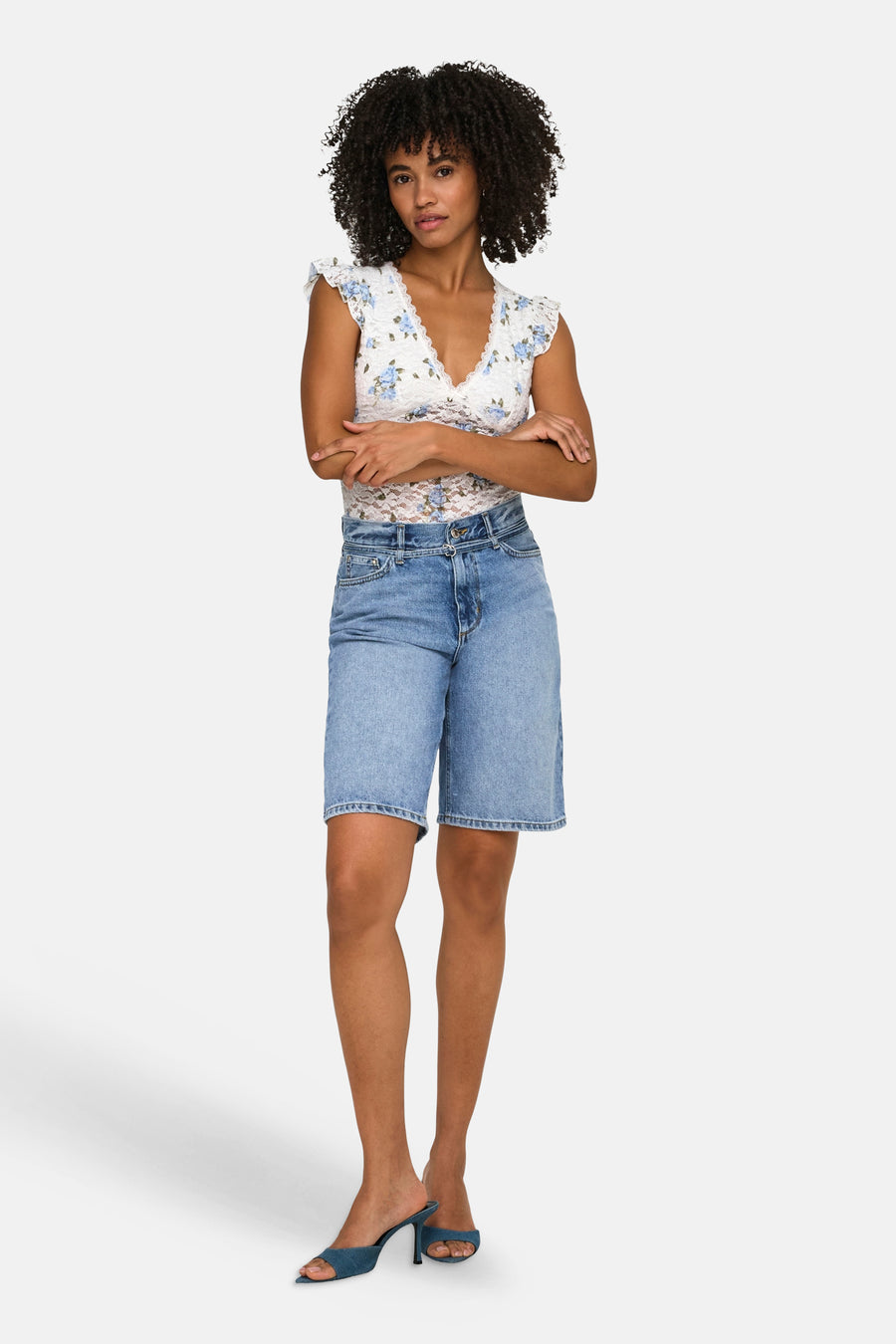 Short en jean bleu moyen ONLY®, longueur genou, porté par un mannequin avec un haut en dentelle blanche.