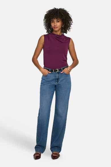 Paarse mouwloze top van ONLY® met watervalhals, gecombineerd met een wijde jeans en bordeauxrode schoenen.