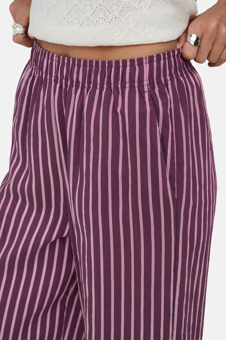 Paarse gestreepte broek van ONLY® met verticale witte en roze strepen, getoond met elastische tailleband en een witte top.