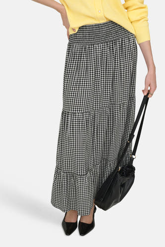 Lange rok van JDY, met zwart-wit pied-de-poule patroon en gelaagd ontwerp, gecombineerd met gele cardigan en zwarte leren tas.
