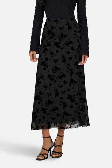Robe longue noire de JDY, avec un motif floral subtil et associée à une chemise noire et des bottes.