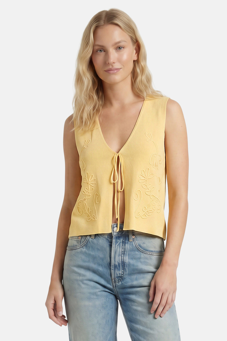 Gele gebreide gilet met bloemenrelief en strikvoorkant van ONLY®, gedragen met lichtblauwe jeans, front view