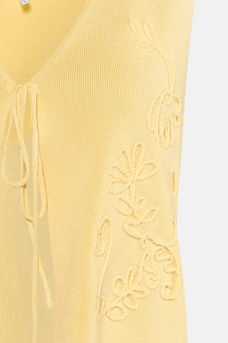 Gele gebreide gilet van ONLY® met bloemenmotief en strikdetail aan de voorkant, close-up weergave