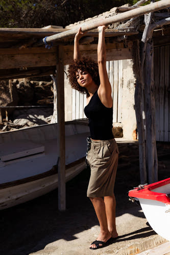 Zwart mouwloos top van ONLY®, strak model, gedragen met beige korte broek en zwarte sandalen, lifestyle shot bij houten steunen.