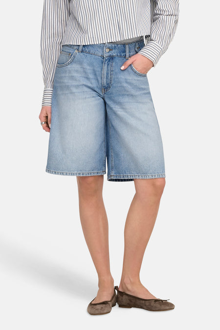 Korte lichtblauwe denim broek van ONLY, gecombineerd met een gestreept overhemd en suède ballerina's.
