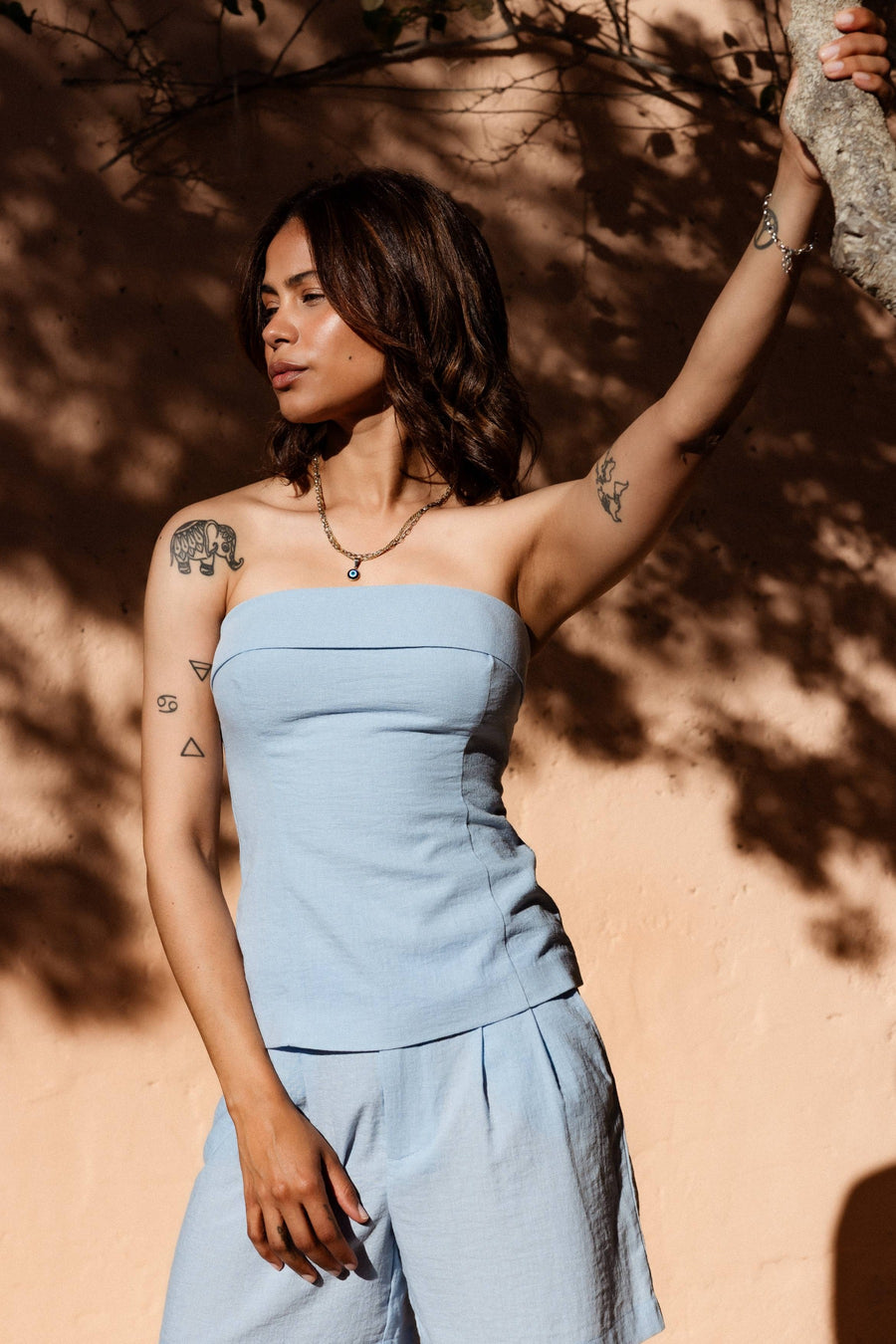Blauwe mouwloze blouse van ONLY® met strakke pasvorm, lichte textuur, en zachte halslijn, gedragen in lifestyle shot tegen zonverlichte muur.