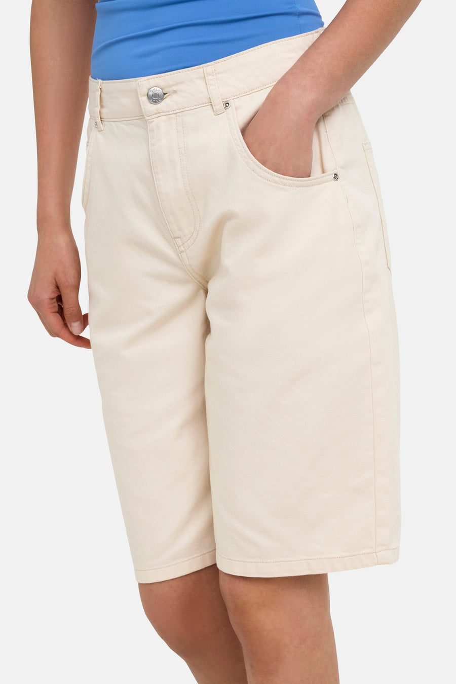 Beige Bermuda shorts van ONLY® met zakken en knoopsluiting, gedragen met blauw topje, zijprofiel.
