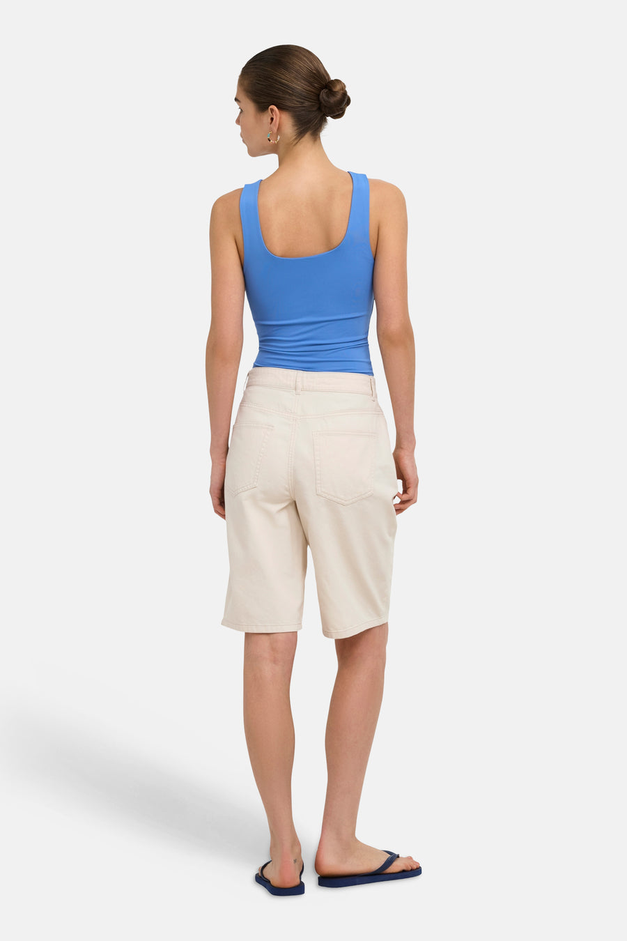 Beige Bermuda shorts van ONLY®, achterzijde, met zakken, model in blauwe top en sandalen