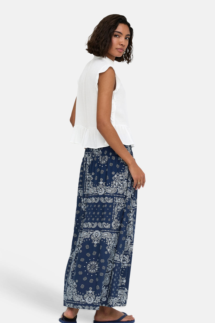 Witte mouwloze blouse met ruches aan de zijkant en zoom, van ONLY®, gedragen met een donkerblauwe paisleyrok, zijaanzicht.