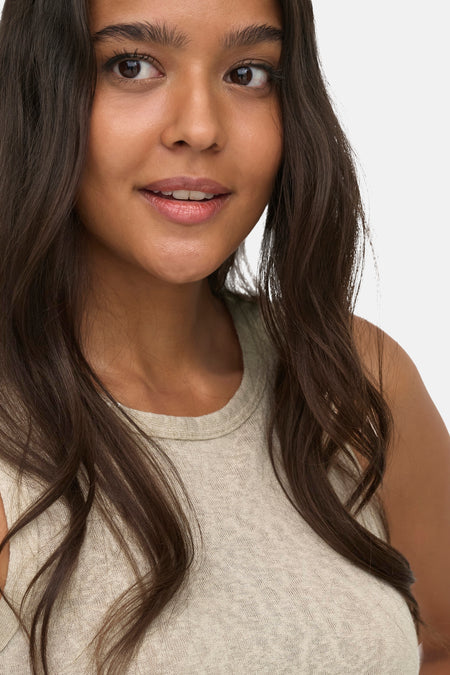 Beige tanktop van ONLY® met ronde hals, zacht textuur, close-up op model met lang donker haar
