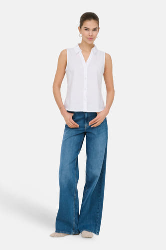 Wijd uitlopende jeans van midblauw denim van ONLY, met wijde pijpen en gedragen met een witte blouse.