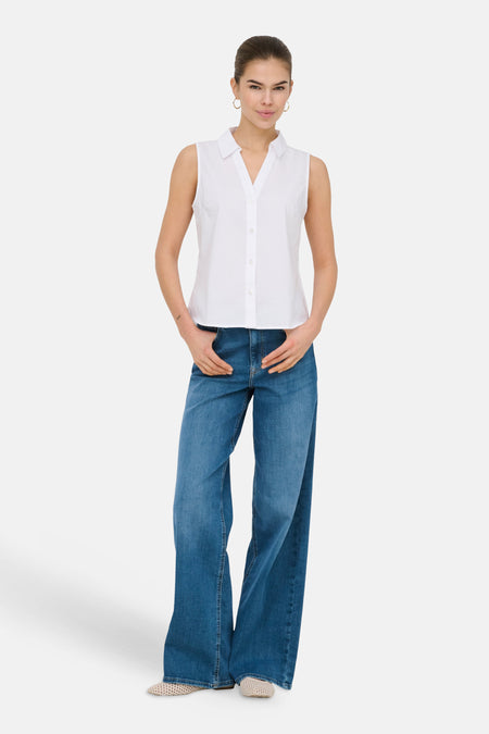 Wijd uitlopende jeans van midblauw denim van ONLY, met wijde pijpen en gedragen met een witte blouse.