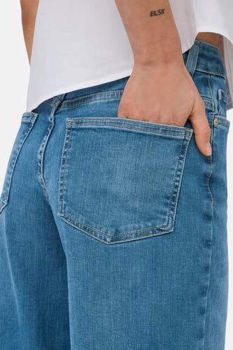 Blauwe wide jeans van ONLY, met een hand in de achterzak, gedragen met een wit shirt.
