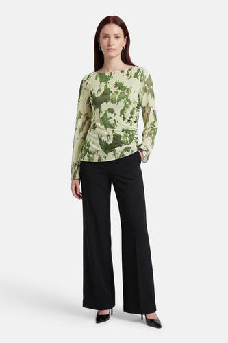 Groene T-shirt met lange mouwen van JDY, met een abstracte camouflageprint, gedragen met zwarte, uitlopende pantalon en pumps.