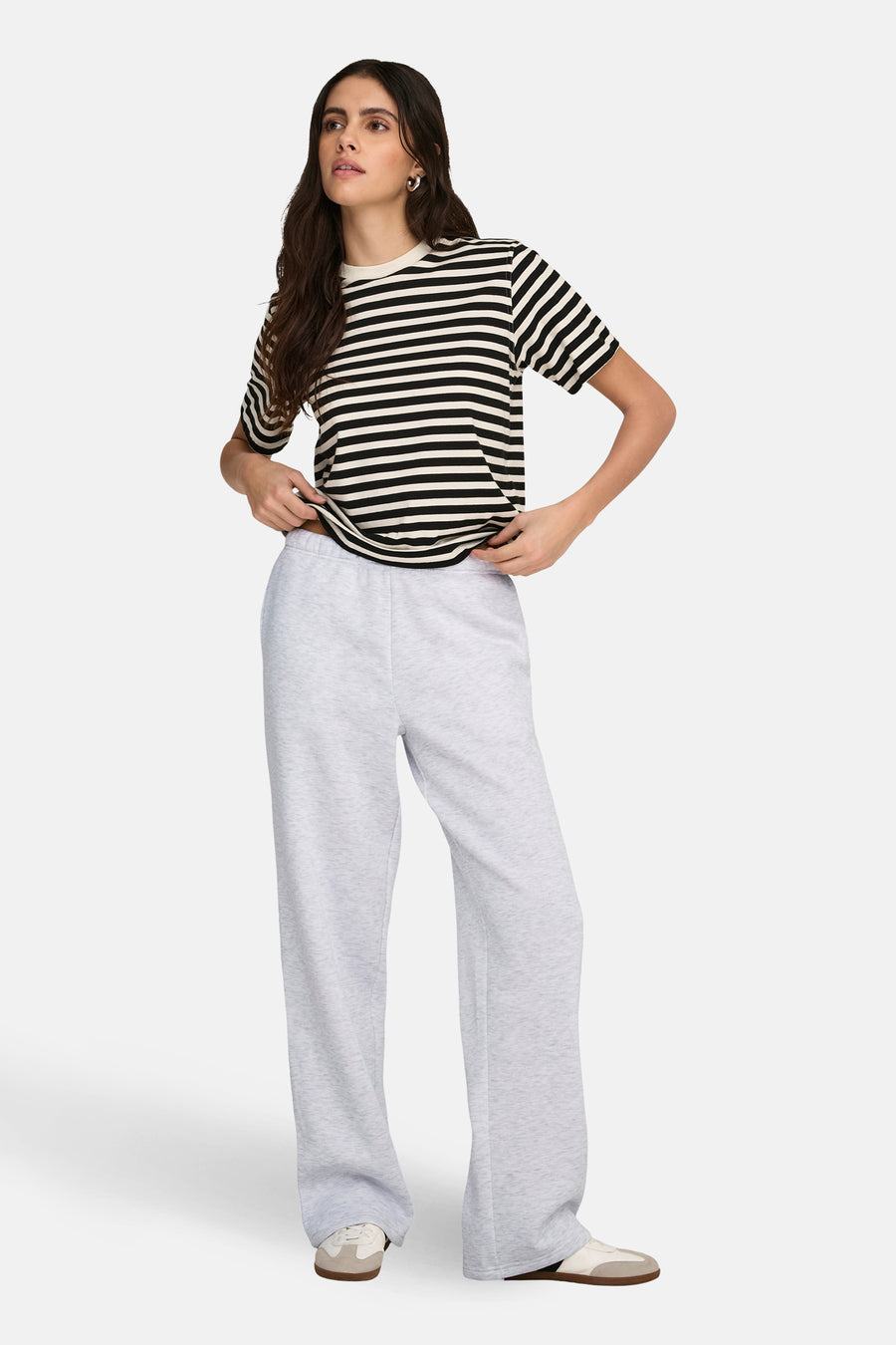 Grijze joggingbroek van ONLY, met wijde pijpen en gecombineerd met een gestreept T-shirt en sneakers.