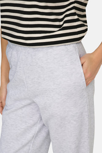 Grijze joggingbroek van ONLY, met een hand in de zak en een gestreept shirt.
