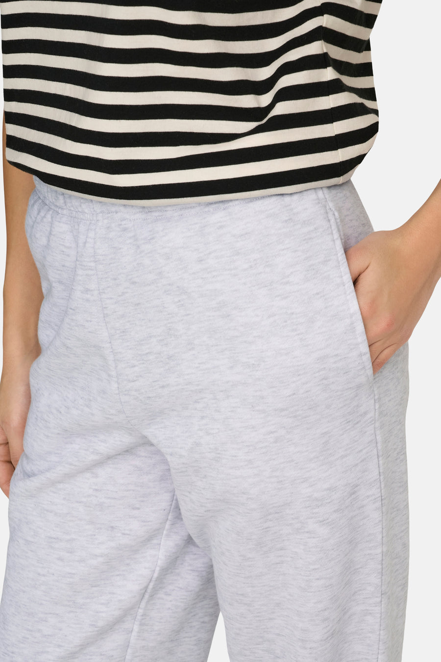 Grijze joggingbroek van ONLY, met een hand in de zak en een gestreept shirt.

