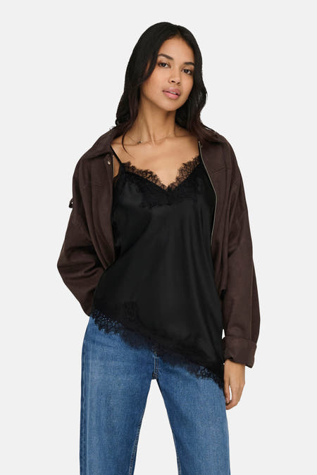Zwarte blouse van ONLY®, met kanten details en een bruin jasje en jeans.
