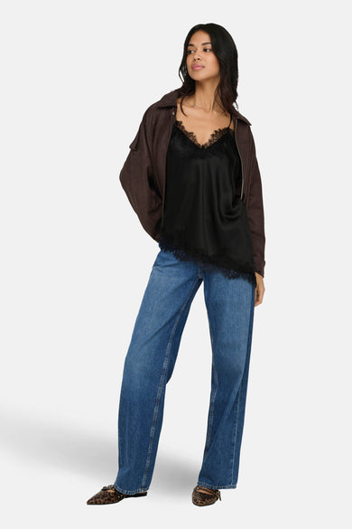 Zwarte blouse zonder mouwen van ONLY, met kanten details, gecombineerd met een bruin jasje en blauwe jeans.