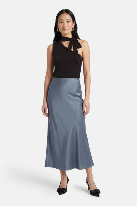 Zwarte geribbelde mouwloze top van JDY met asymmetrische hals en strikdetail, gecombineerd met een satijnen midi-rok.