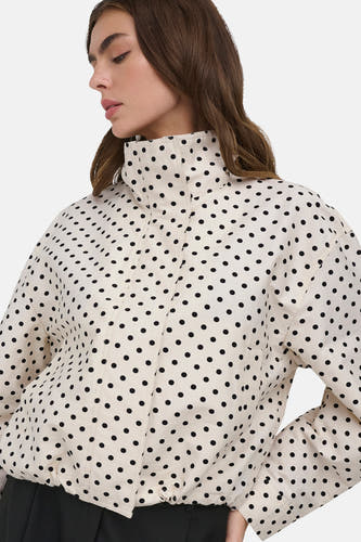Veste courte blanche ONLY® à pois noirs, col montant et fermeture à glissière, portée par un mannequin.